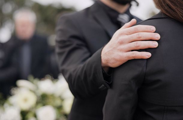 Funerale, supporto e persone che si occupano di dolore, lutto o madre depressa alla cerimonia di sepoltura, al servizio commemorativo o al cimitero. Mano, spalla e uomo che aiuta una donna triste con amore, consigli o conforto familiare.