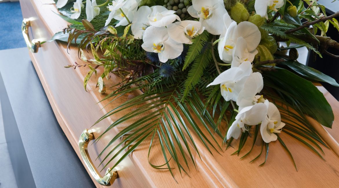 Una bara con una composizione floreale in un obitorio